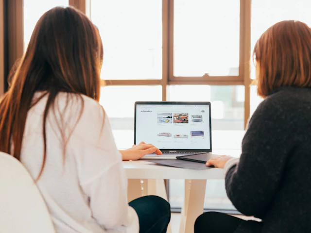 Two people discussing a project while looking at a laptop