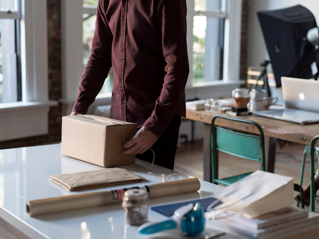 Hands holding a cardboard shipping box on a table